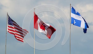 Canada, USA, and Quebec flags waving in the wind cloudy day