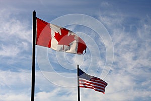 Canadian and American flag on blue sky