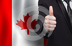 Canadian concept. Businessman showing thumb up on the background of flag of Canada