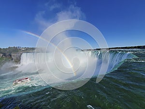 A Canadian cruise ship with lots of people in red rain coat approaching the famous Niagara Falls