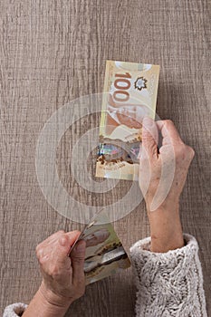 Canadian currency. Dollars. Above view of old retired person pay