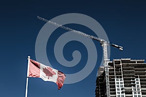 Canadian flag with apartment building under construction in the background, Canadian economy and housing market photo