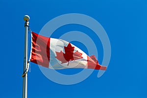 A Canadian flag against a solid blue sky