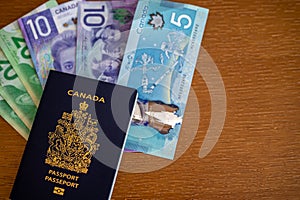 Canadian passport with Canadian money on brown background