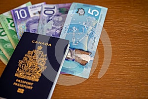Canadian passport with Canadian money on brown background