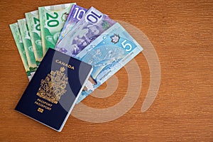 Canadian passport with Canadian money on brown background