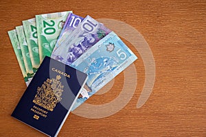 Canadian passport with Canadian money on brown background