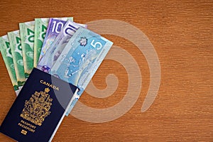 Canadian passport with Canadian money on brown background