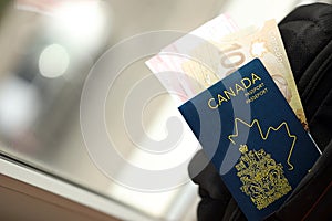 Canadian passport and dollar money bills with airline tickets on backpack