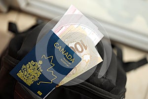 Canadian passport and dollar money bills with airline tickets on backpack