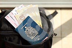 Canadian passport and dollar money bills with airline tickets on backpack