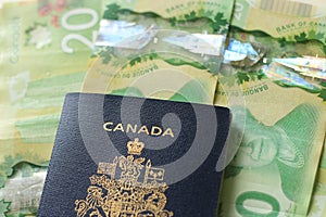 Canadian passport laying on top of twenty dollar bills. Concept of immigrating or emigrating, or travelling with a canadian