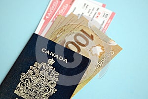 Canadian passport with money and airline tickets on blue background close up