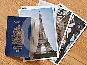 Canadian passport with selection of Parisian travel photos on wooden table