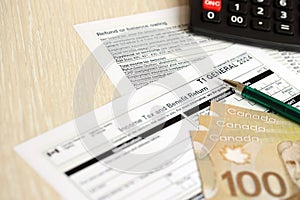 Canadian T1 General tax form Income tax and benefit return lies on table with canadian money bills