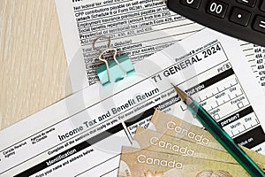 Canadian T1 General tax form Income tax and benefit return lies on table with canadian money bills