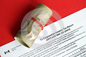 Canadian T2 tax form Corporation income tax return lies on table with canadian money bills