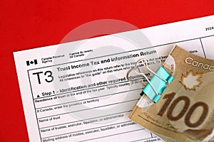 Canadian T3 tax form Trust income tax and information return lies on table with canadian money