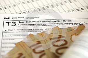 Canadian T3 tax form Trust income tax and information return lies on table with canadian money