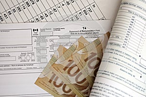 Canadian T4 tax form Statement of remuneration paid lies on table with canadian money bills