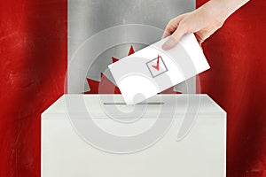 Canadian Vote concept. Voter hand holding ballot paper for election vote on polling station photo