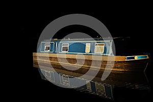 Canal barge narrow boat reflected in water. Isolated on black background