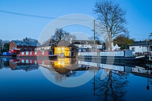 Canal boat dry dock for narrowboat moored repairs at night illuminated and lit up reflecting on long exposure still River Trent