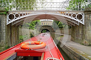 Canal narrowboat passing under iron bridge