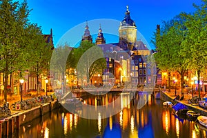 Canal and St Nicholas Church in Amsterdam at twilight, Netherlands. Famous Amsterdam landmark near Central Station