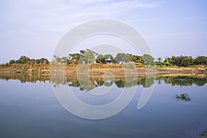 Canal with trees and vegetation reflected in the water nearby Padma river