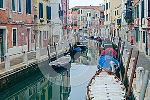Canal in Venice, Italy with parked boats and pedestrian area