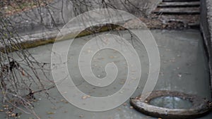 Canal water pollution, river canal with muddy white water, flows down the steps. Waste rubber tires in water