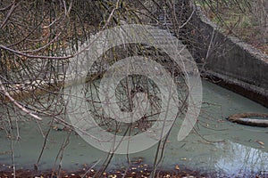 Canal water pollution, river canal with muddy white water, flows down the steps. Waste rubber tires in water