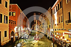 Canal waterway in Venice at night with moving boat and leaning church tower San Giorgio de Greci