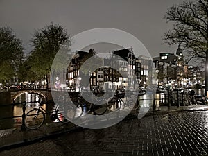 Canals, bridge, bike and houses of Amsterdam city, in Holland, Netherlands at night