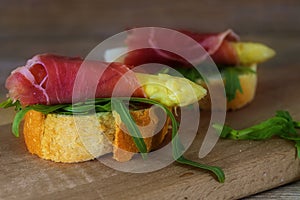 Canape with asparagus, ham and rocket salad isolated on a rustic