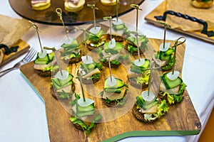 Canape with salted lard, onion, cucumber, rye bread and parsley. Catering banquet table with different food snacks