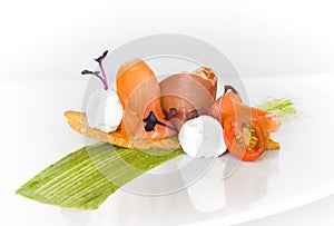 canape with smoked salmon, spanish jamÃ³n, cherry tomato and cheese cream with avocado sauce on a white background. photo