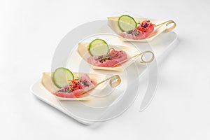 Canapes in boats with tuna and cucumber on a white background. Catering service