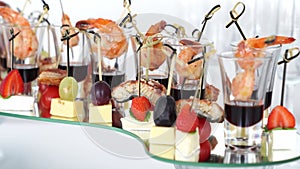 canapes of cheese with fruit, fish with tomatoes and shrimp with sauce in glass.