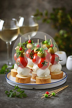 Canapes of mozzarella, green olives, cherry tomatoes, parsley on croutons of white bread.