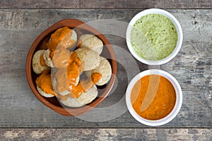 Canarian potatoes (papas arrugadas) with mojo sauce on wooden table photo