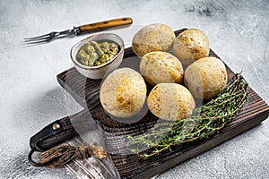 Canary Islands dish Papas Arrugadas, wrinkly potatoes with Mojo verde green sauce. White background. Top view