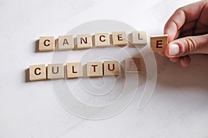 Cancel culture society concept. Cancel culture text made of letter blocks on white background. Hand holding one letter.