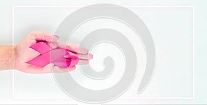 Cancer awareness. Health care symbol pink ribbon in woman hands on white background. Breast woman support concept. World