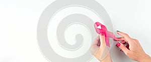 Cancer awareness. Health care symbol pink ribbon in woman hands on white background. Breast woman support concept. World