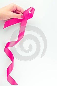 Cancer day. Health care symbol pink ribbon in woman hands on white background. Breast cancer support concept with copy