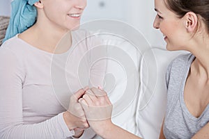 Cancer patient and her friend holding hands