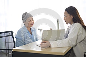 Cancer patient woman wearing head scarf after chemotherapy consulting and visiting doctor in hospital