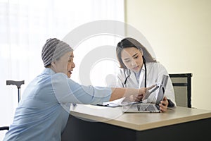 Cancer patient woman wearing head scarf after chemotherapy consulting and visiting doctor in hospital